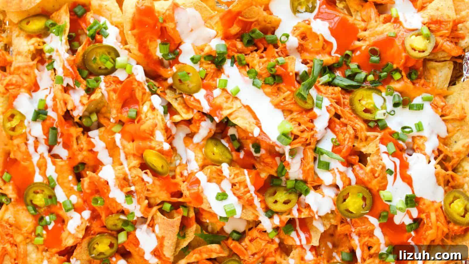 35 Game-Day Recipes to Win Your Season’s Food Lineup 33 Close-up of loaded Buffalo chicken nachos piled high with shredded chicken, jalapeños, cheese, green onions, hot sauce, and a dollop of sour cream.