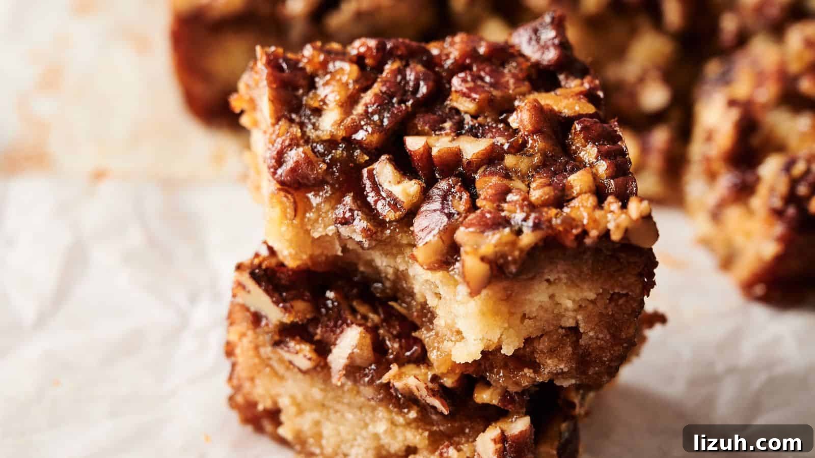 35 Game-Day Recipes to Win Your Season’s Food Lineup 7 Two pecan-topped dessert bars are stacked on parchment paper, showing a dense, crumbly base and a caramelized nut topping.