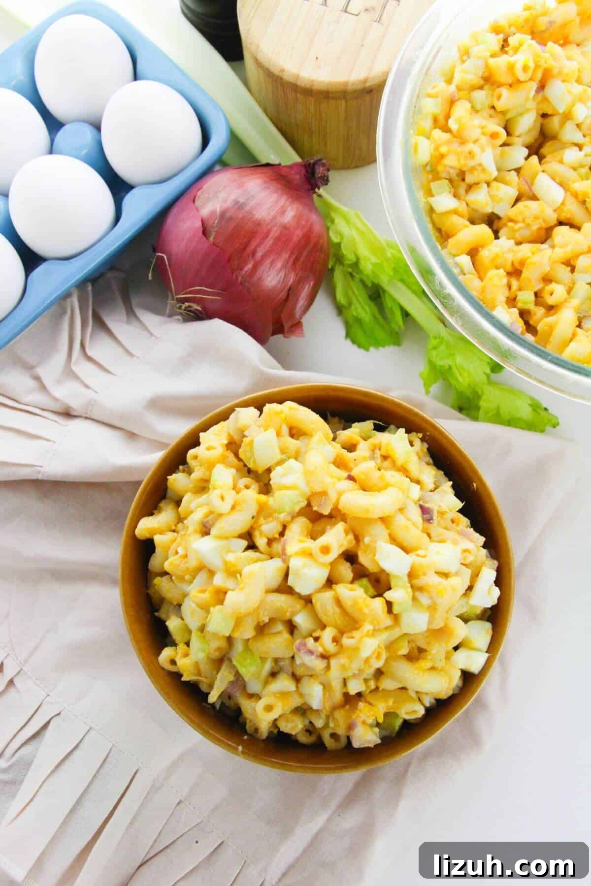 A bowl of the side celery, and red onion sits beside a tray of eggs, a whole red onion, celery stalks.