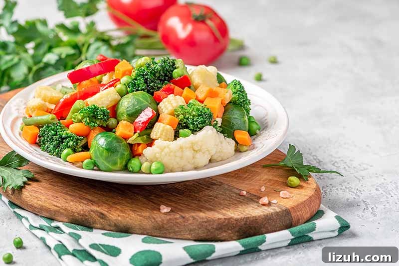 9 Delicious Tricks to Boost Flavor in Steamed Vegetables 12 Horizontal image of a plateful of cooked plain cauliflower, brussels sprouts, peas, broccoli, and peppers.
