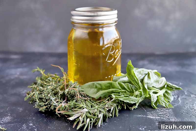 9 Delicious Tricks to Boost Flavor in Steamed Vegetables 5 Vertical image of a jar of golden yellow oil with a metal collar and top, with sprigs of fresh rosemary and basil around the base.