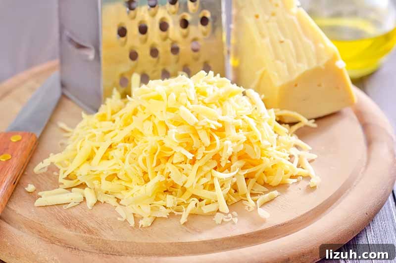 9 Delicious Tricks to Boost Flavor in Steamed Vegetables 8 Horizontal image of shredded cheese on a wooden block next to a grater.