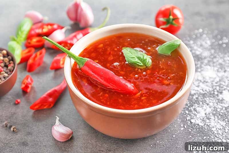 9 Delicious Tricks to Boost Flavor in Steamed Vegetables 9 Horizontal image of a spicy red sauce in a bowl on a table next to peppers.