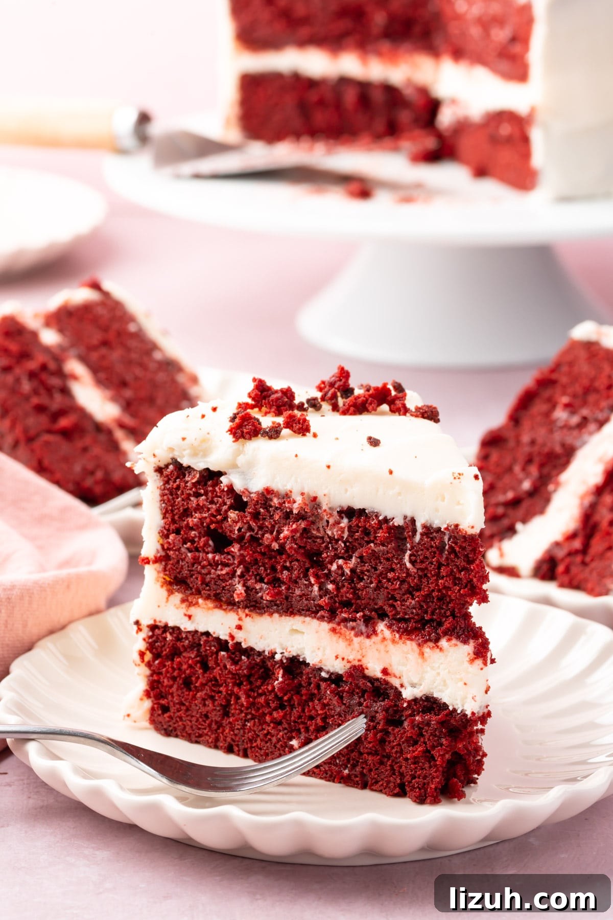 Gluten-Free Red Velvet Cake Recipe: Moist, Rich & Simple to Make 2 A slice of red velvet cake on a plate with a fork with more slices behind it.