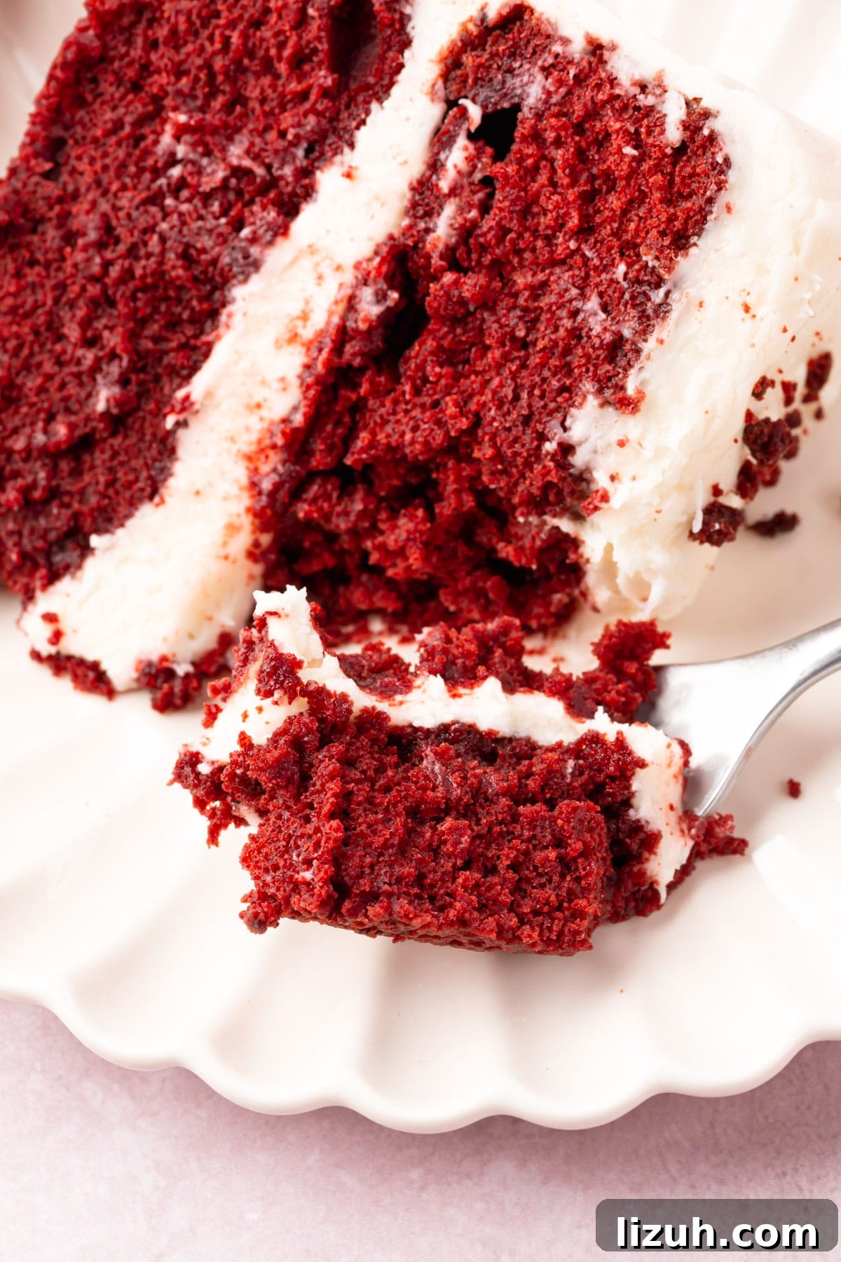 Gluten-Free Red Velvet Cake Recipe: Moist, Rich & Simple to Make 15 A piece of red velvet cake on a plate with a fork digging into the cake.