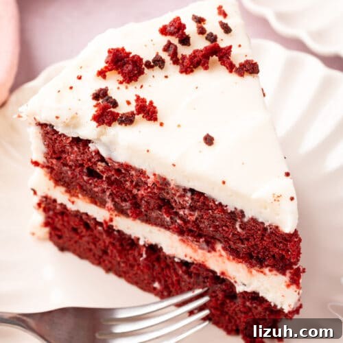 Gluten-Free Red Velvet Cake Recipe: Moist, Rich & Simple to Make 16 A slice of gluten-free red velvet cake on a plate frosted with cream cheese frosting and topped with a sprinkle of cake crumbs.