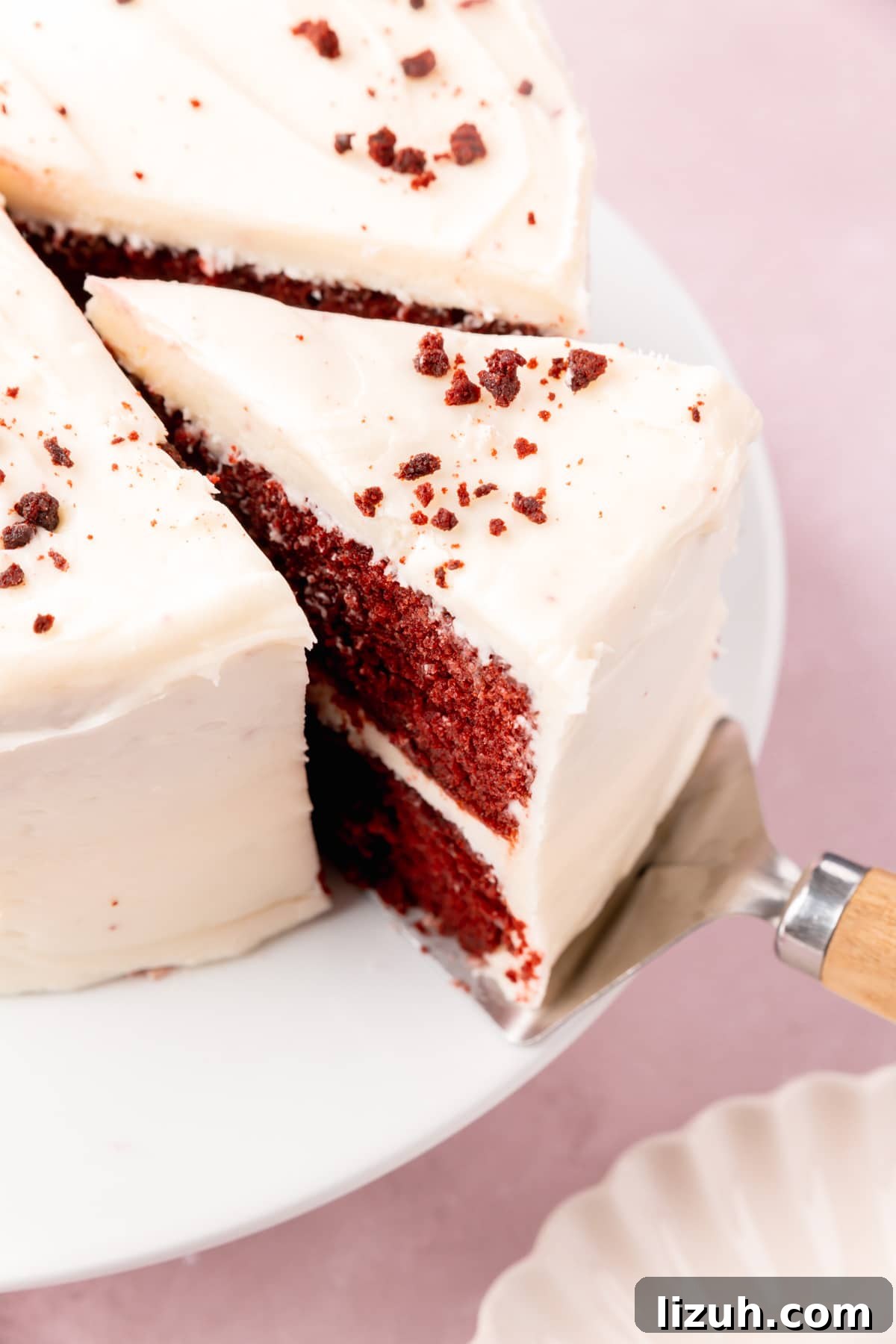 Gluten-Free Red Velvet Cake Recipe: Moist, Rich & Simple to Make 17 A slice of red velvet cake being pulled from the rest of the cake with a cake server.