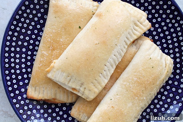 Four pizza pockets sitting on a dark blue plate with white polka dots.