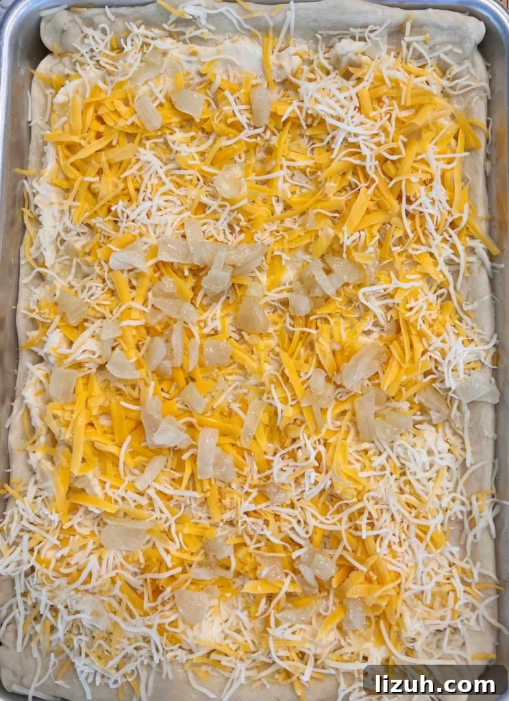 unbaked pierogi pizza with mashed potatoes, cheese and onions on baking sheet