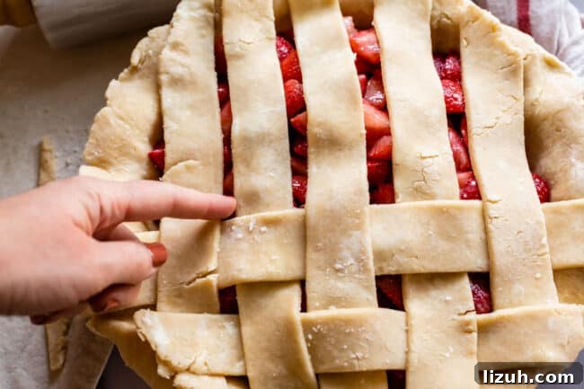 finger pointing to the next strip of pie dough that needs to be pulled back for lattice crust