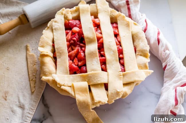 folding back strips of pie dough to make a lattice pie crust on strawberry pie