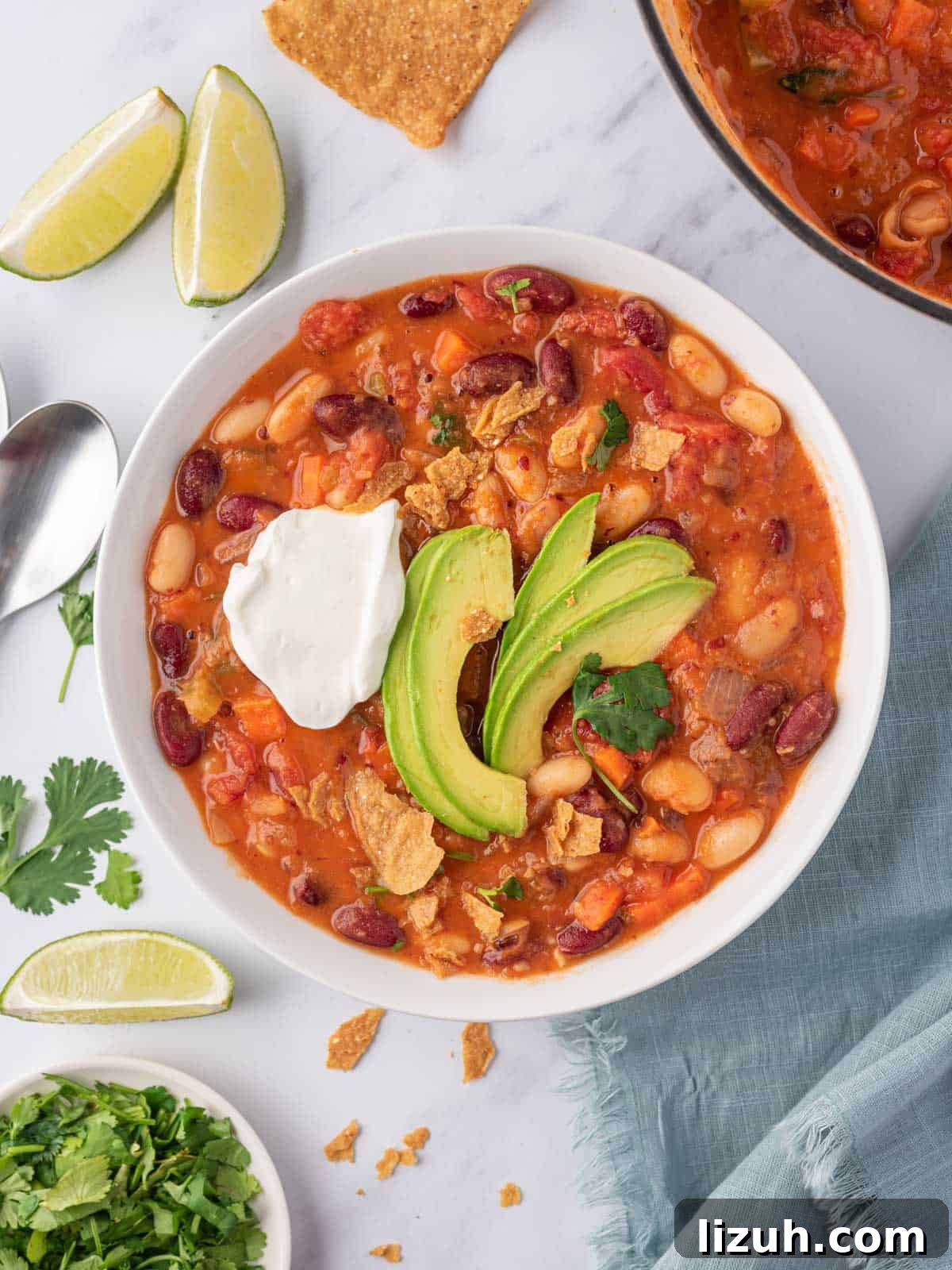 A bowl of easy vegan chili garnished with avocado, cilantro and vegan sour cream.