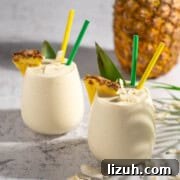 Ultra-Creamy Piña Colada Smoothie — No Banana, No Ice 10 Two pina colada smoothies with a pineapple in the background.