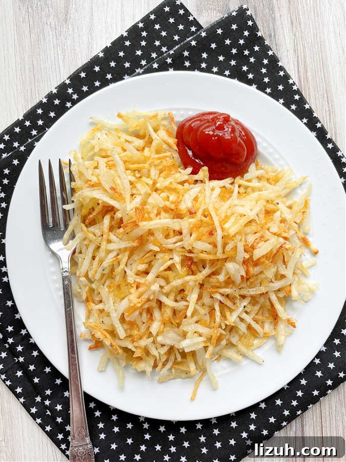 Air Fryer Frozen Hash Browns: Crispy in 15 Minutes 2 air fryer shredded hashbrowns plated with ketchup