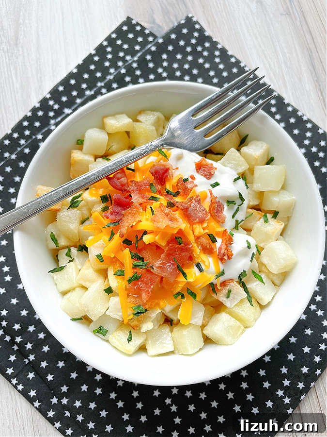 Air Fryer Frozen Hash Browns: Crispy in 15 Minutes 3 air fryer cubed hashbrowns in a bowls topped with bacon, cheese and sour cream