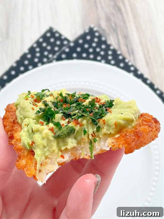 Air Fryer Frozen Hash Browns: Crispy in 15 Minutes 5 taking a bite of an air fried hashbrown pattie topped with mashed avocado