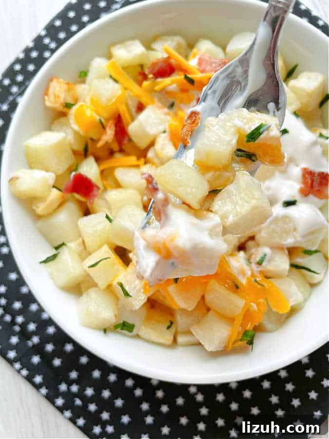 Air Fryer Frozen Hash Browns: Crispy in 15 Minutes 10 taking a bite of loaded hashbrown potatoes that were cooked in the air fryer