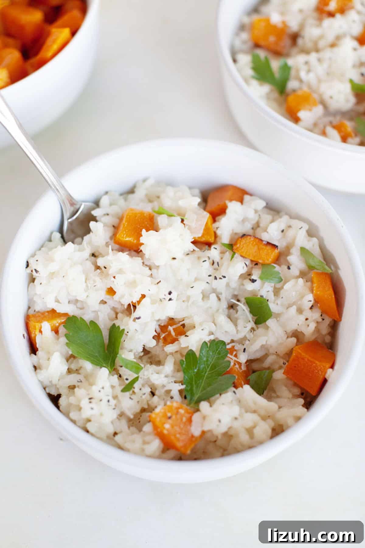 Two bowls of butternut squash risotto with carrots and parsley.