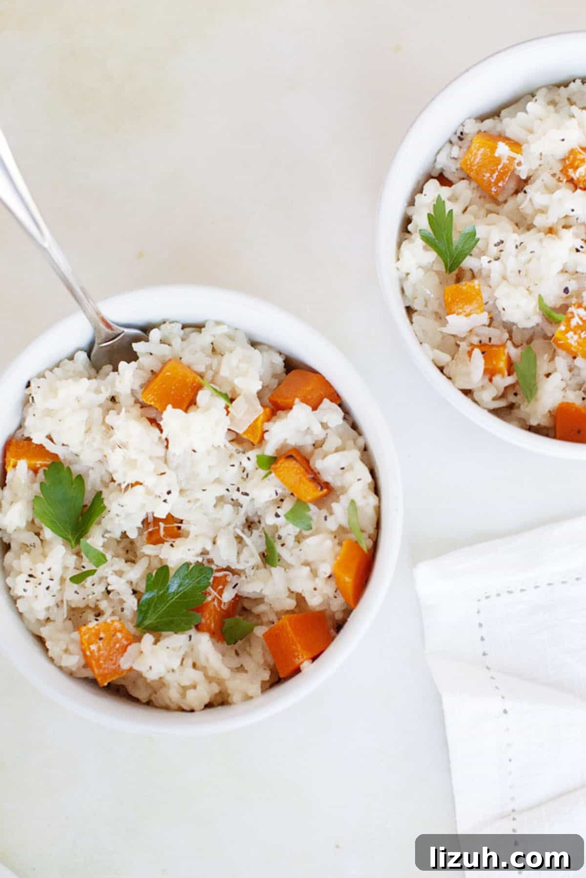 Two bowls of butternut squash risotto with carrots and parsley.