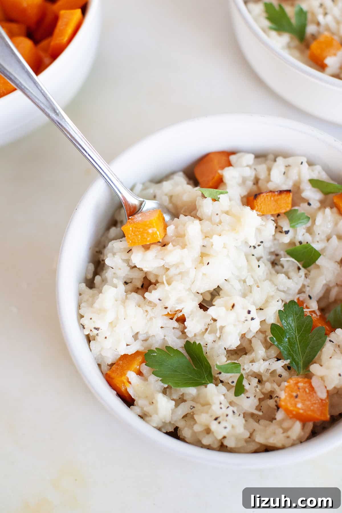 Two bowls of butternut squash risotto with carrots and parsley.