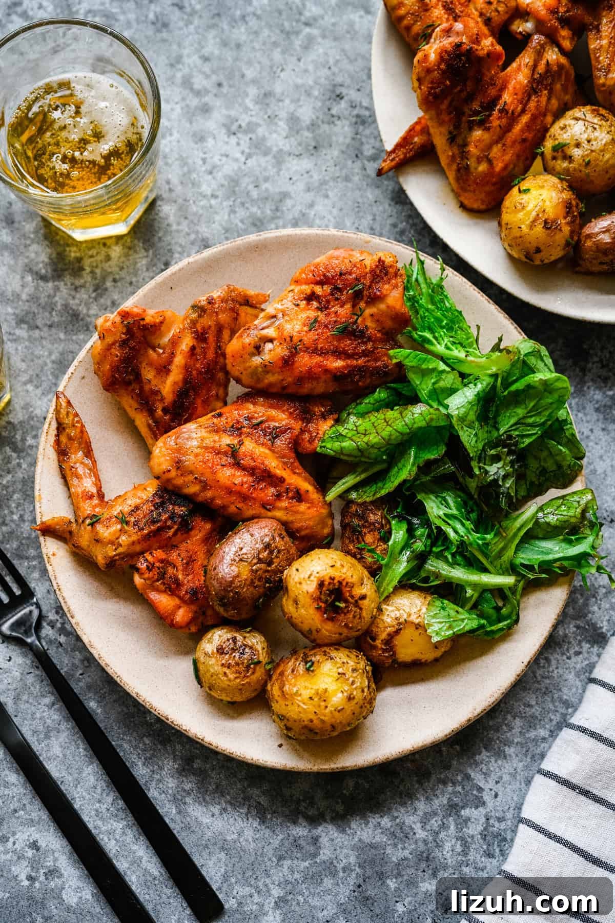 Crispy Oven-Baked Chicken Wings with Garlic and Herbs 8 A plate with greens, potatoes, and baked whole chicken wings.
