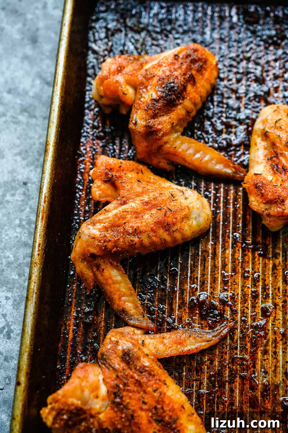 Crispy Oven-Baked Chicken Wings with Garlic and Herbs 9 Three baked chicken wings on a sheet pan.
