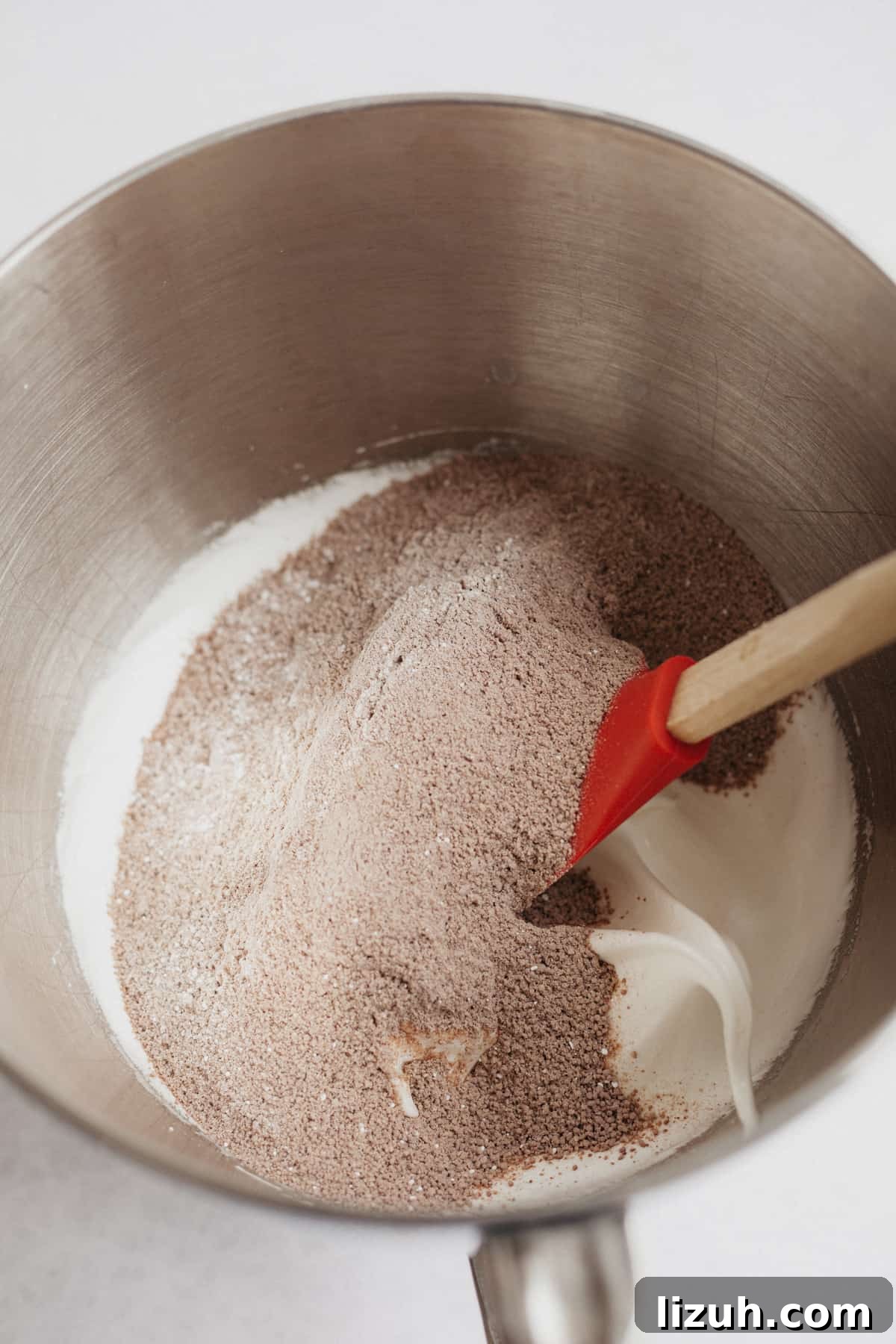Nutella-Filled Chocolate Macarons: Classic French Cookie Recipe 7 A large silver mixing bowl with meringue and cocoa powder