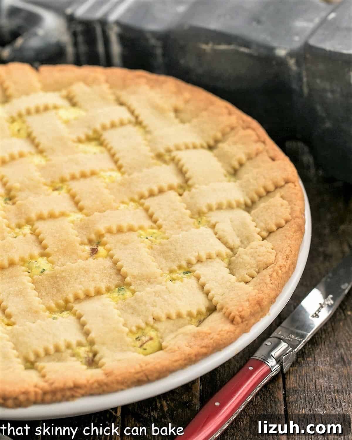 Classic Italian Pizza Rustica Recipe: Savory Rustic Pie Guide 2 Close view of uncut pizza rustica in a white ceramic pie plate with a red handle knife.