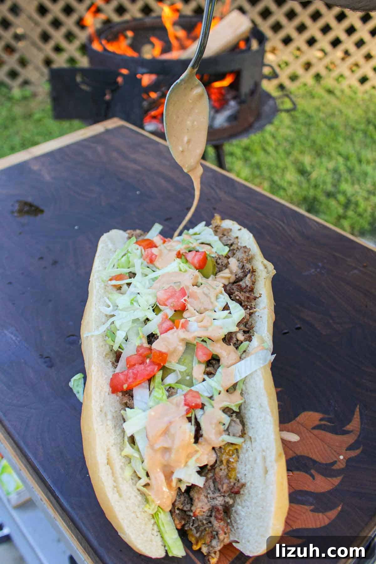 Animal Style Cheesesteak getting drizzled with the special sauce.