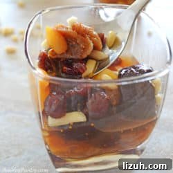 A spoon scooping some of the dried fruits of a khoshaf cup