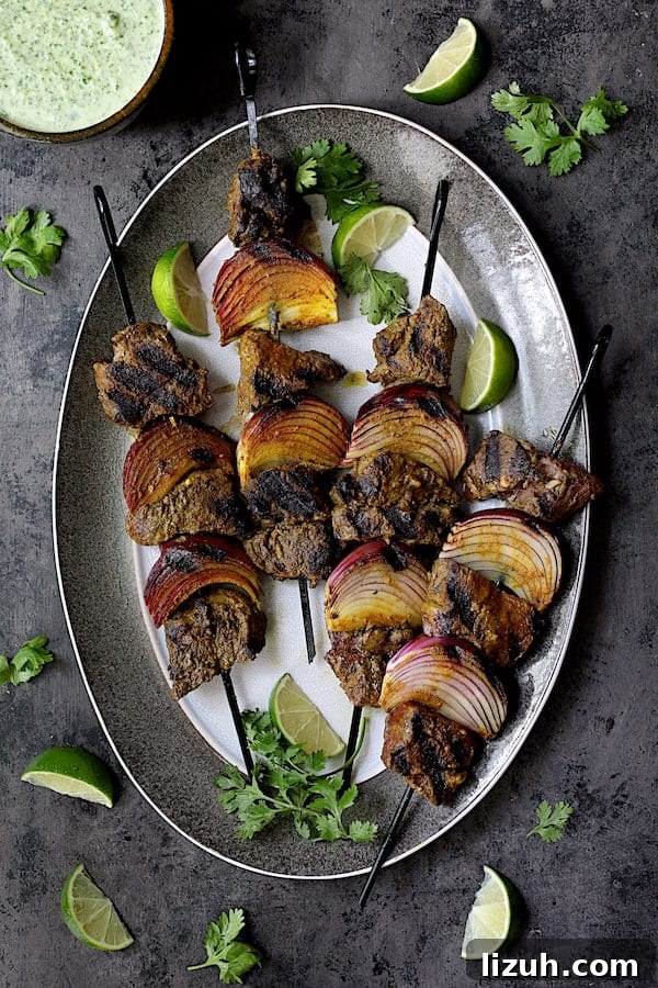 Indian Beef Kabobs with Cilantro Coconut Sauce recipe 2 Indian-Style Beef Kabobs with Cilantro-Coconut Sauce - Overhead shot of cooked kabobs on gray-rimmed platter garnished with lime wedges and cilantro