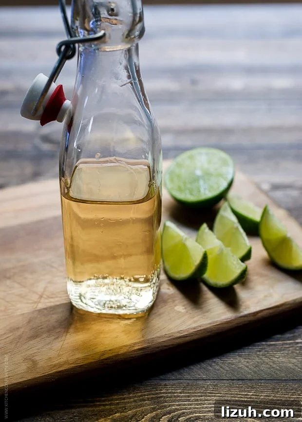 Pumpkin Spice Dark and Stormy Cocktail Recipe 3 A glass bottle of ginger beer and slices of lime on a wooden surface.