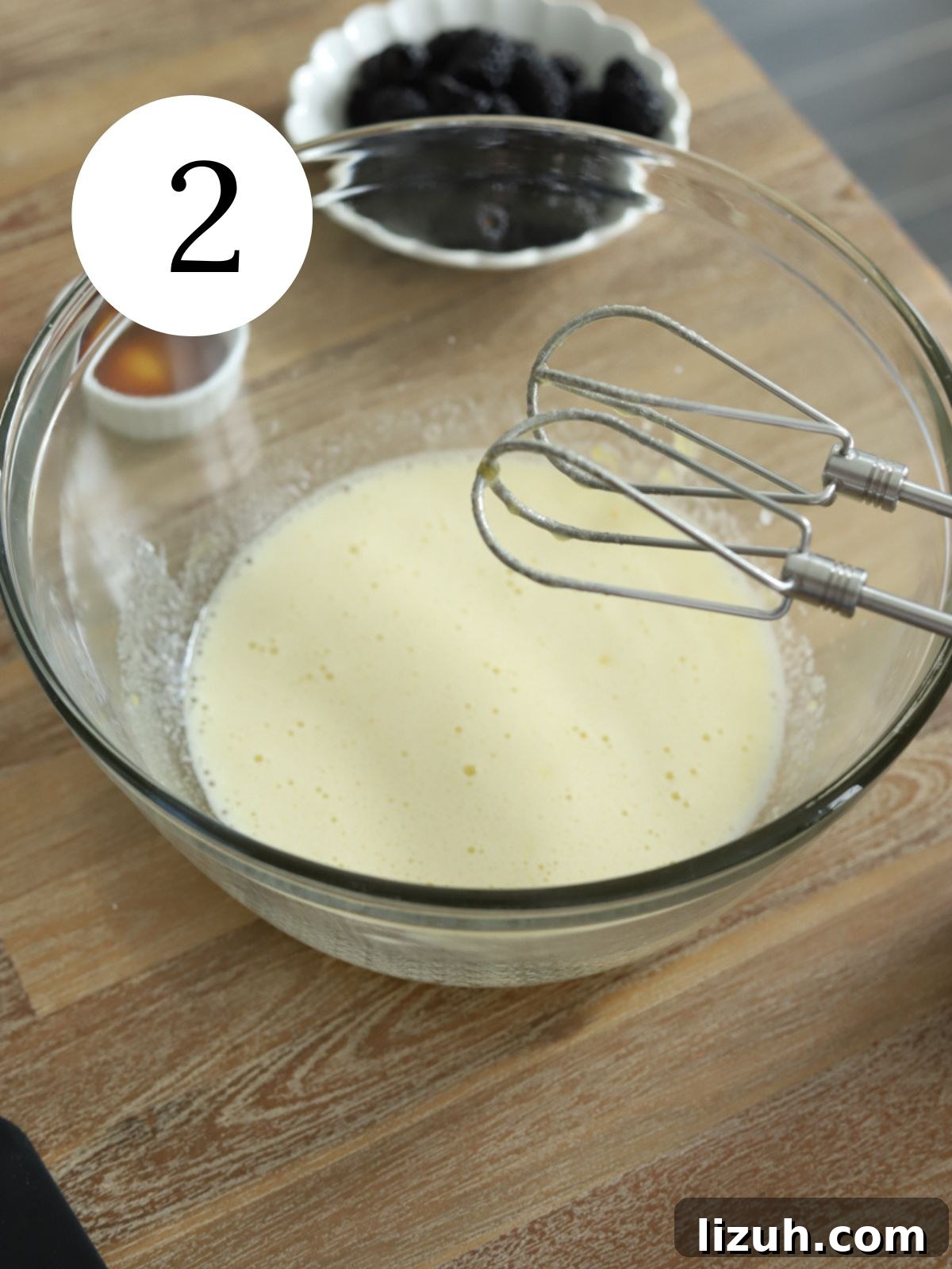 Moist Blackberry Almond Cake Recipe with Crisp Almond Topping 5 A glass mixing bowl with sugar and eggs mixed together with a mixer next to some blackberries.