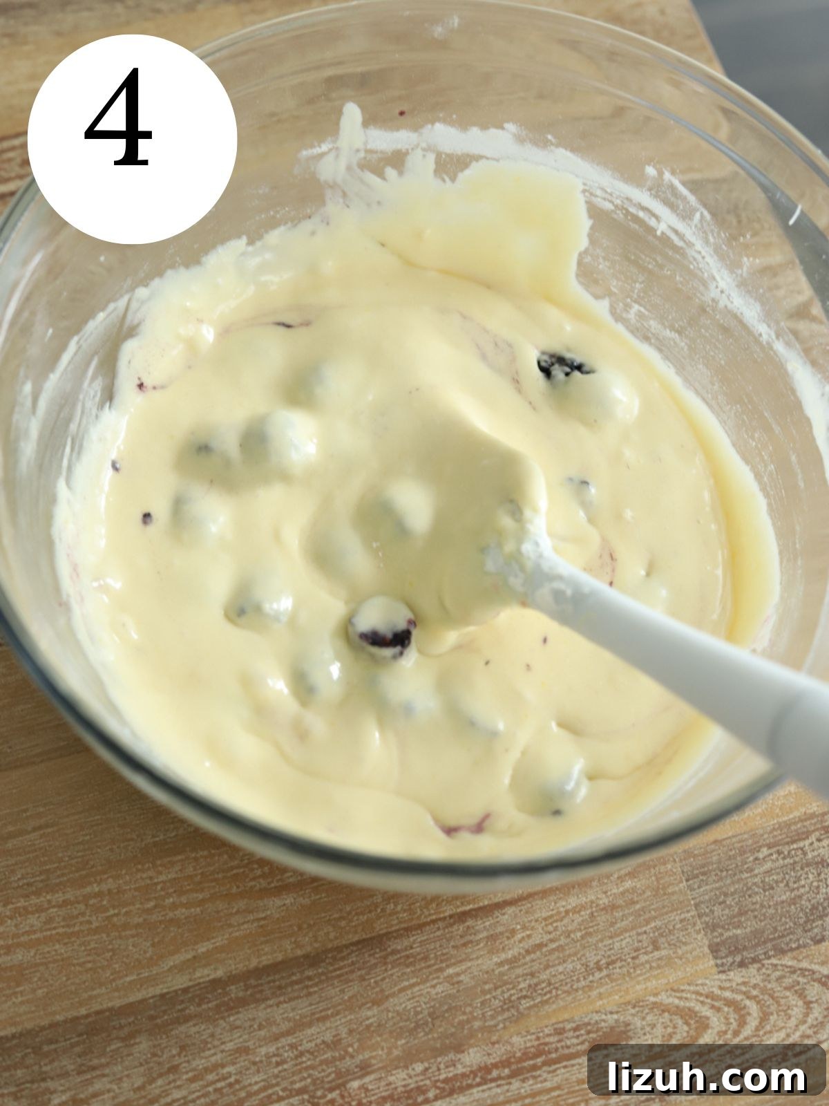 Moist Blackberry Almond Cake Recipe with Crisp Almond Topping 7 A glass mixing bowl with blackberries being stirred into cake batter with a spatula.