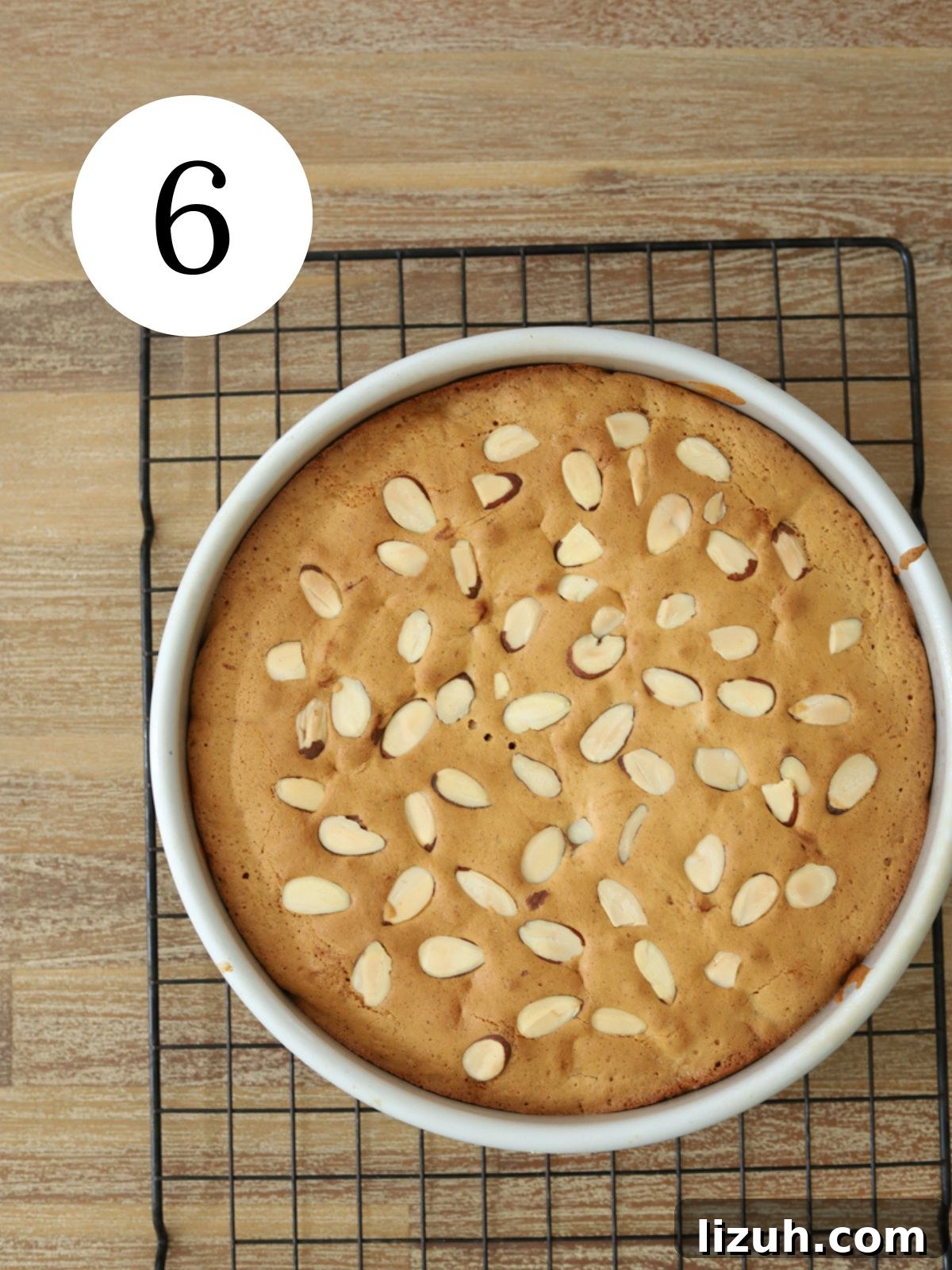 Moist Blackberry Almond Cake Recipe with Crisp Almond Topping 9 A golden cake topped with almonds in a round pan set on a wire rack.