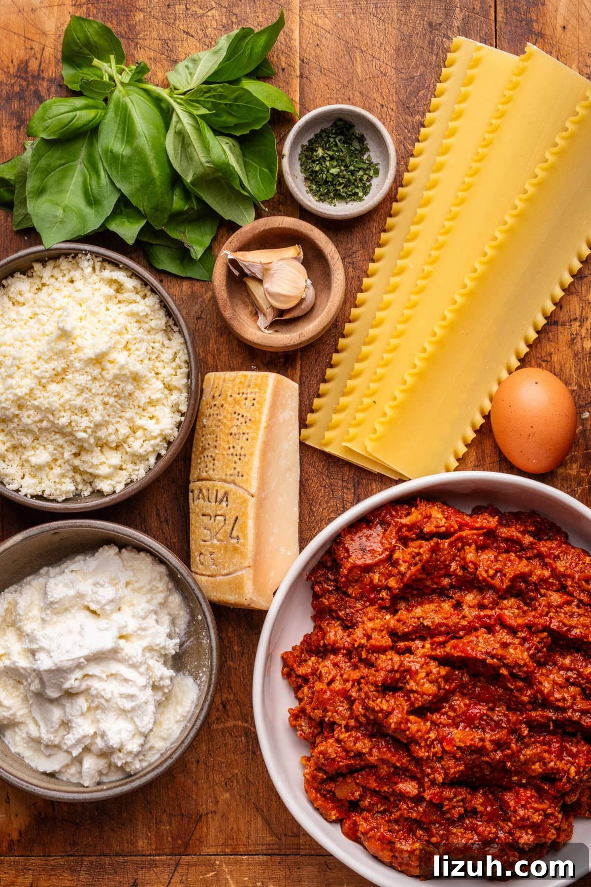 Ingredients for lasagna bolognese with ricotta displayed on a wooden background.