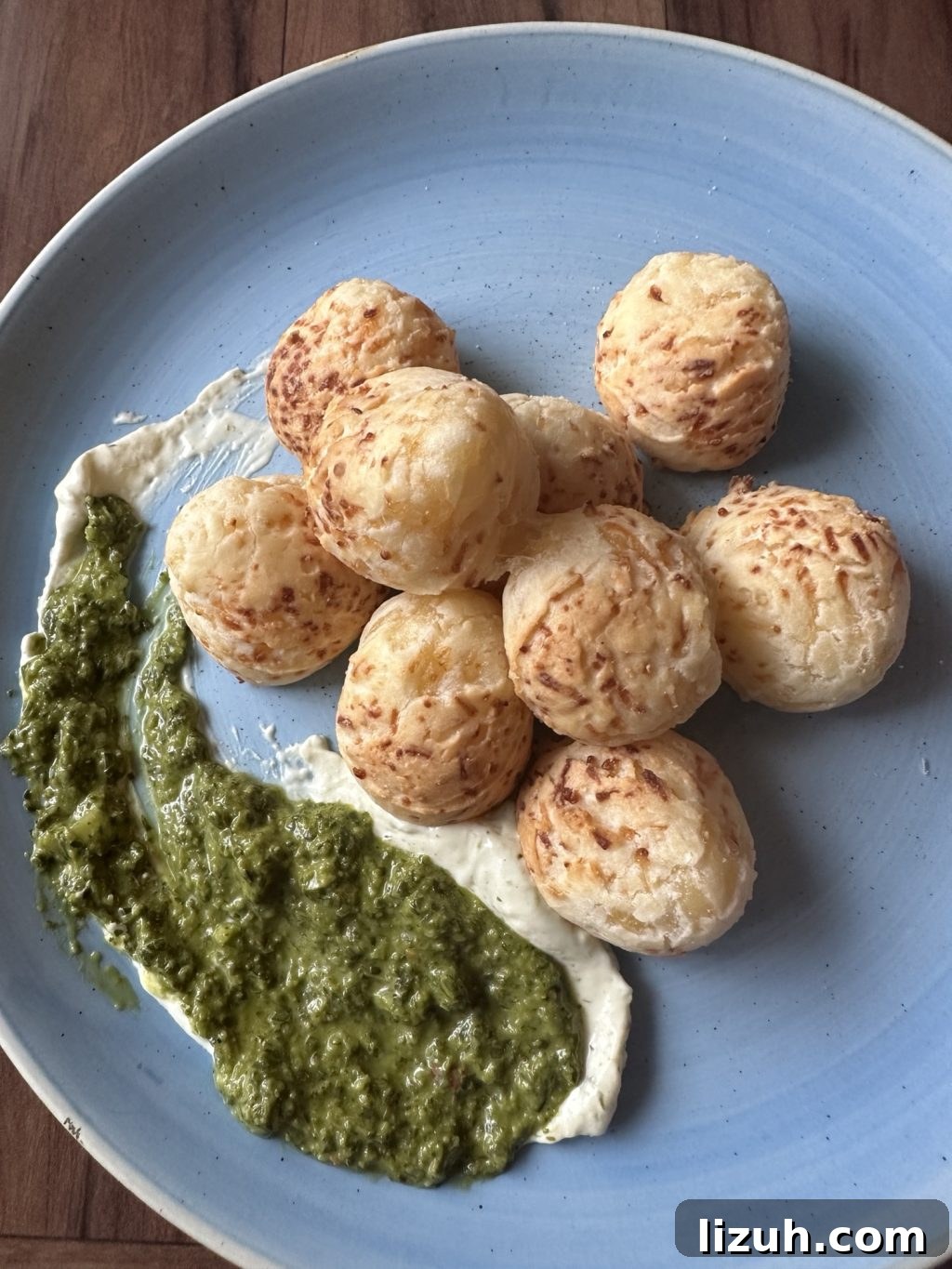 Dough balls with a green and white sauce on a blue plate