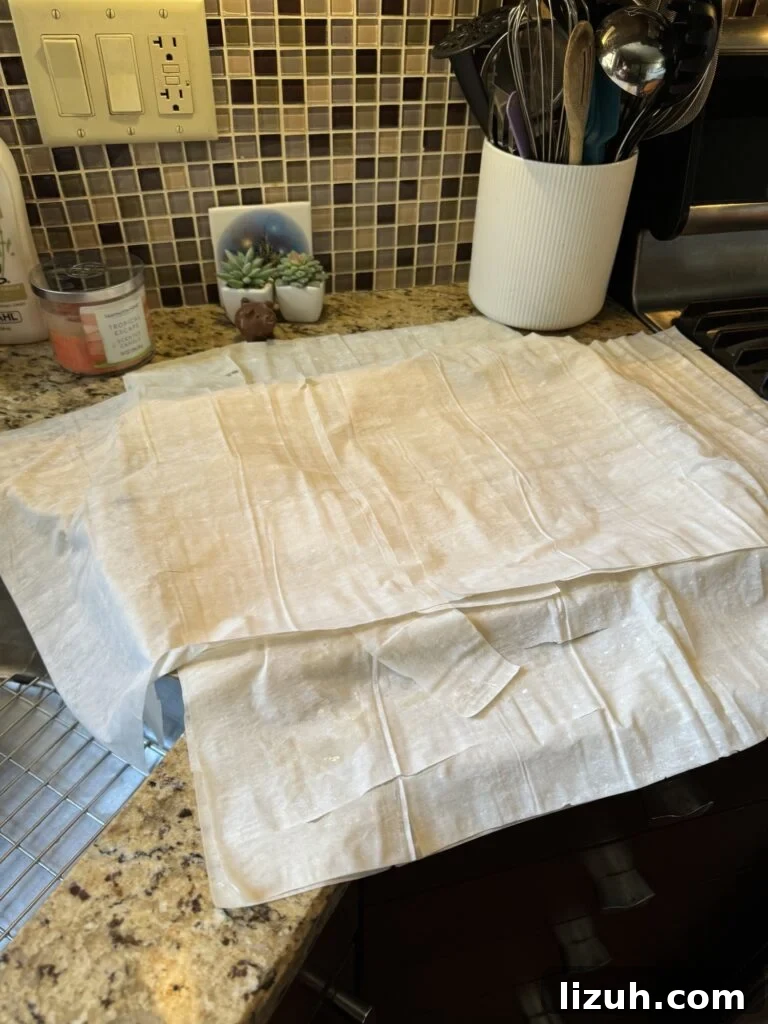 Layers of Phyllo dough layered on top of a baking sheet on a kitchen counter