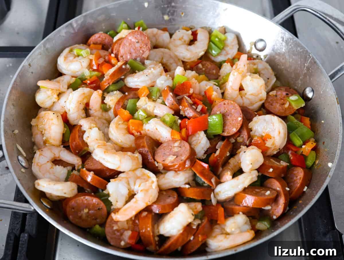 Overhead shot of the shrimp, sausage and vegetables cooking in the skillet. 