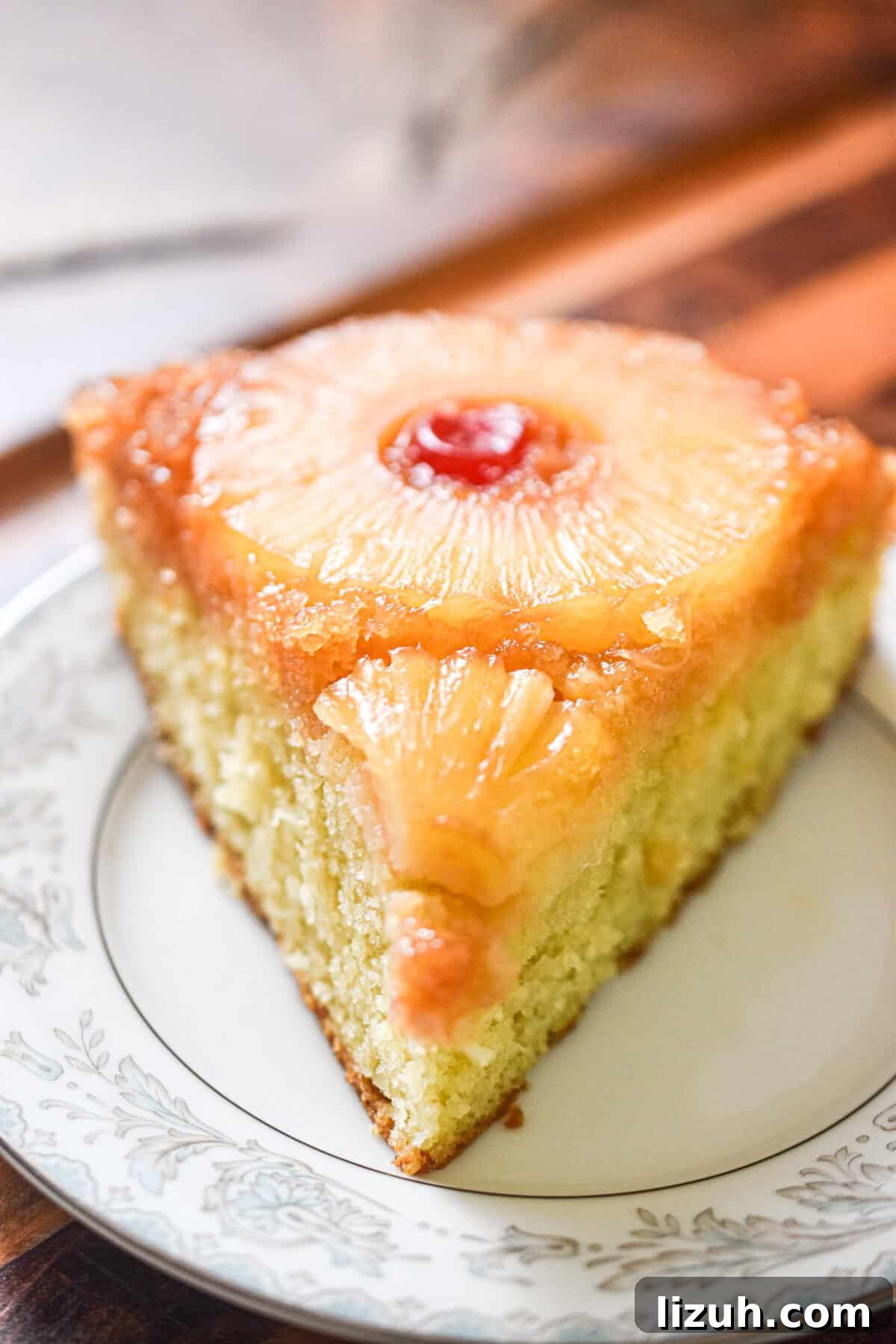Sourdough Pineapple Upside-Down Cake Recipe for Moist, Tangy Loaf 9 A slice of the sourdough pineapple upside down cake is on a plate on a wooden background.
