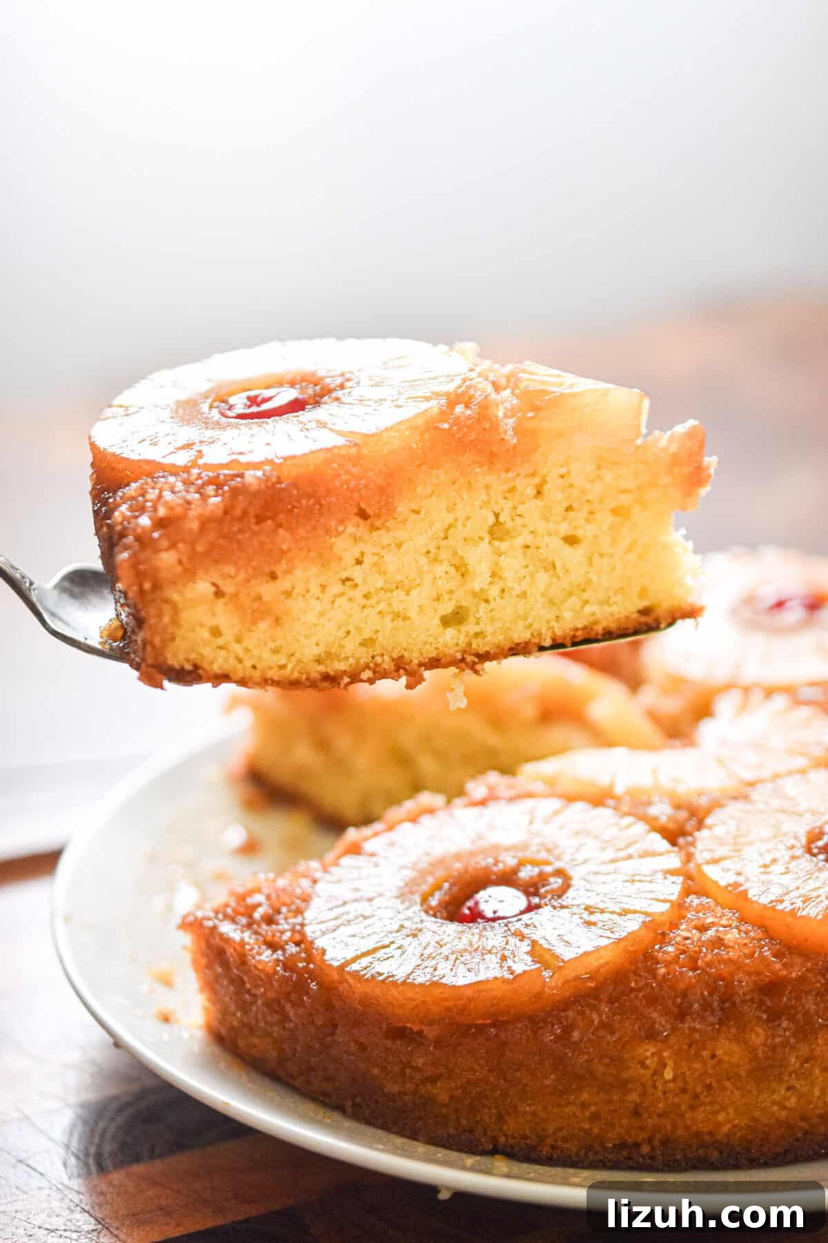 Sourdough Pineapple Upside-Down Cake Recipe for Moist, Tangy Loaf 10 A pie slicer is holding a piece of the cake.