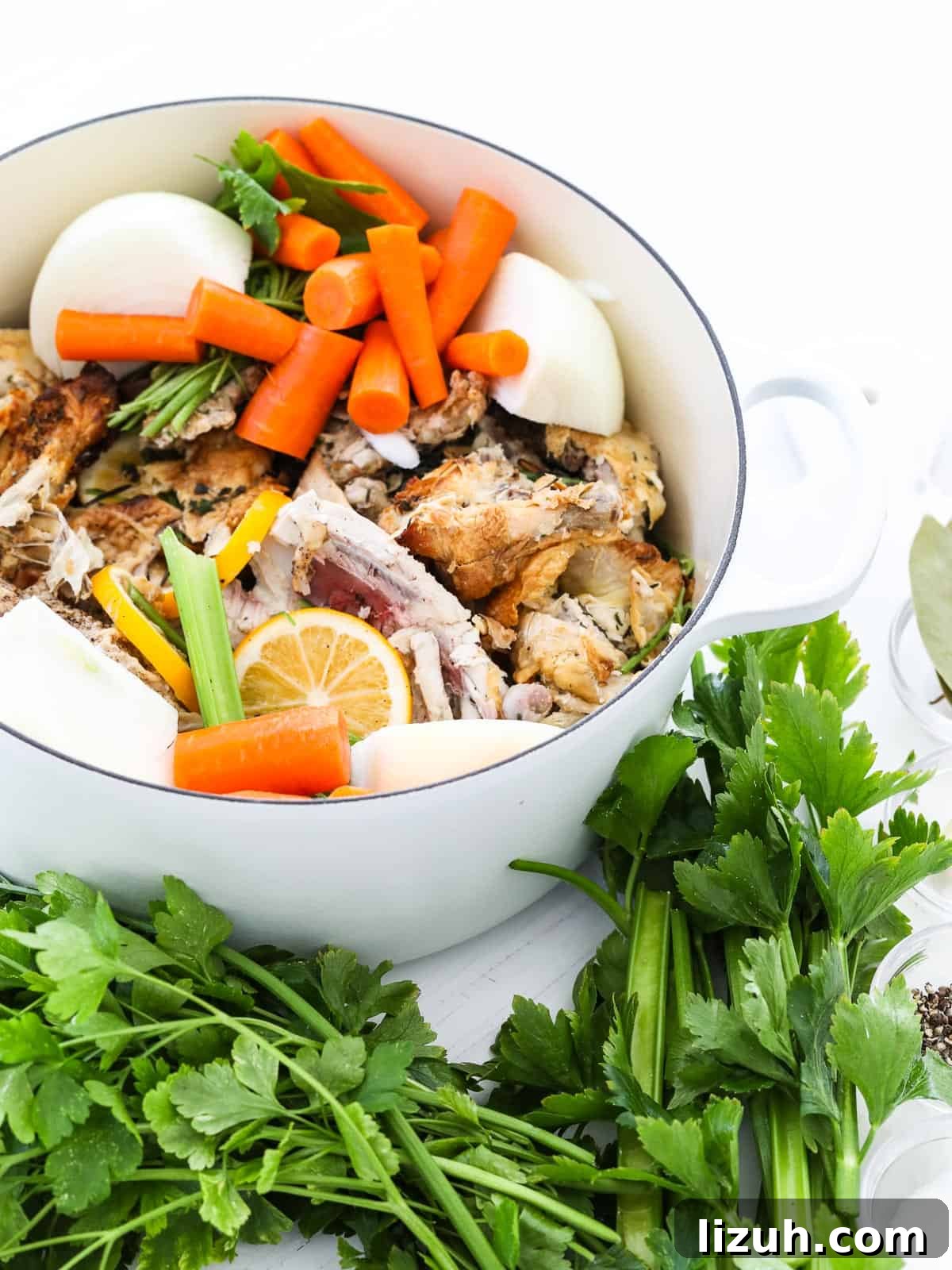 Homemade Chicken Bone Broth Recipe: Rich, Slow-Simmered Stock 3 A large white cooking pot filled with ingredients to make chicken stock at home.