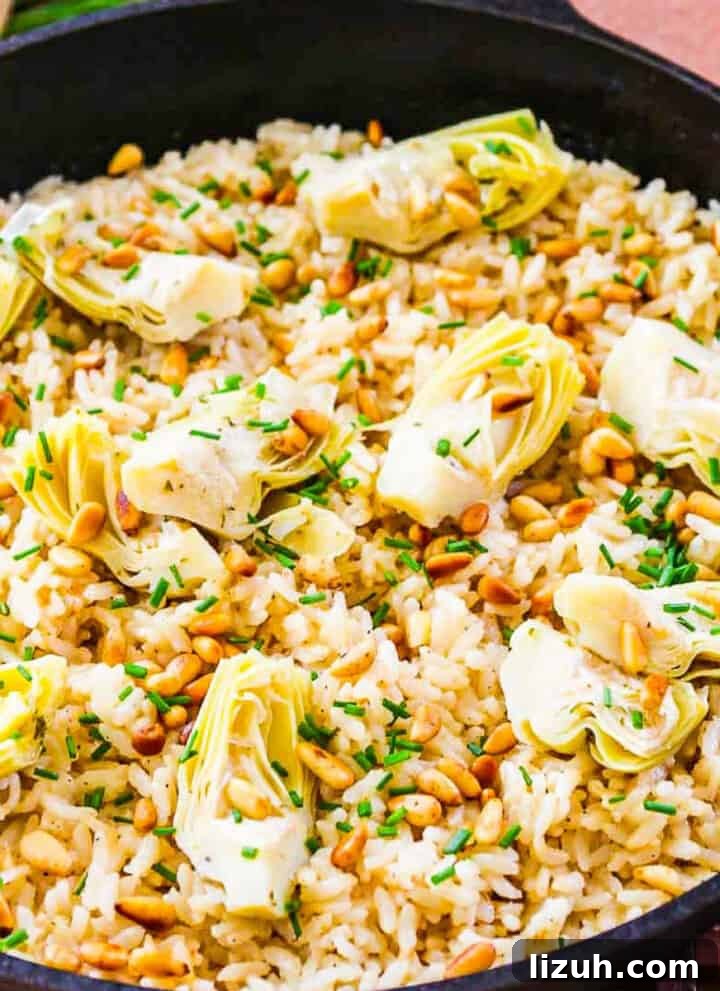 A black cast iron pan with risotto made from arborio rice topped with artichokes and pine nuts.