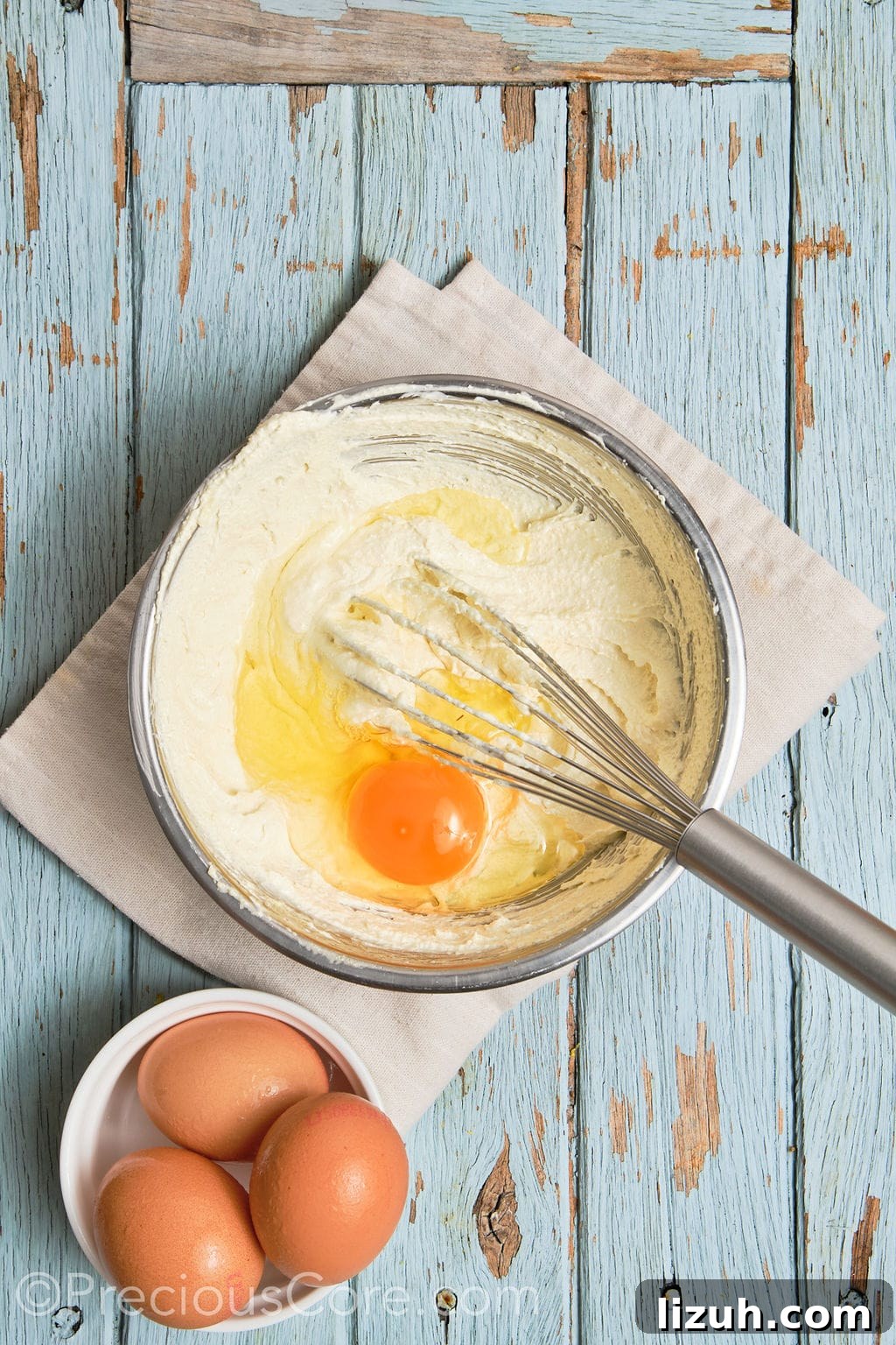 eggs whisked into a creamed butter mixture in a bowl.