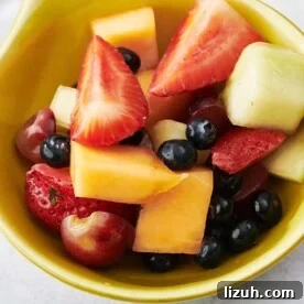 Mixed fruit salad in small yellow bowl.