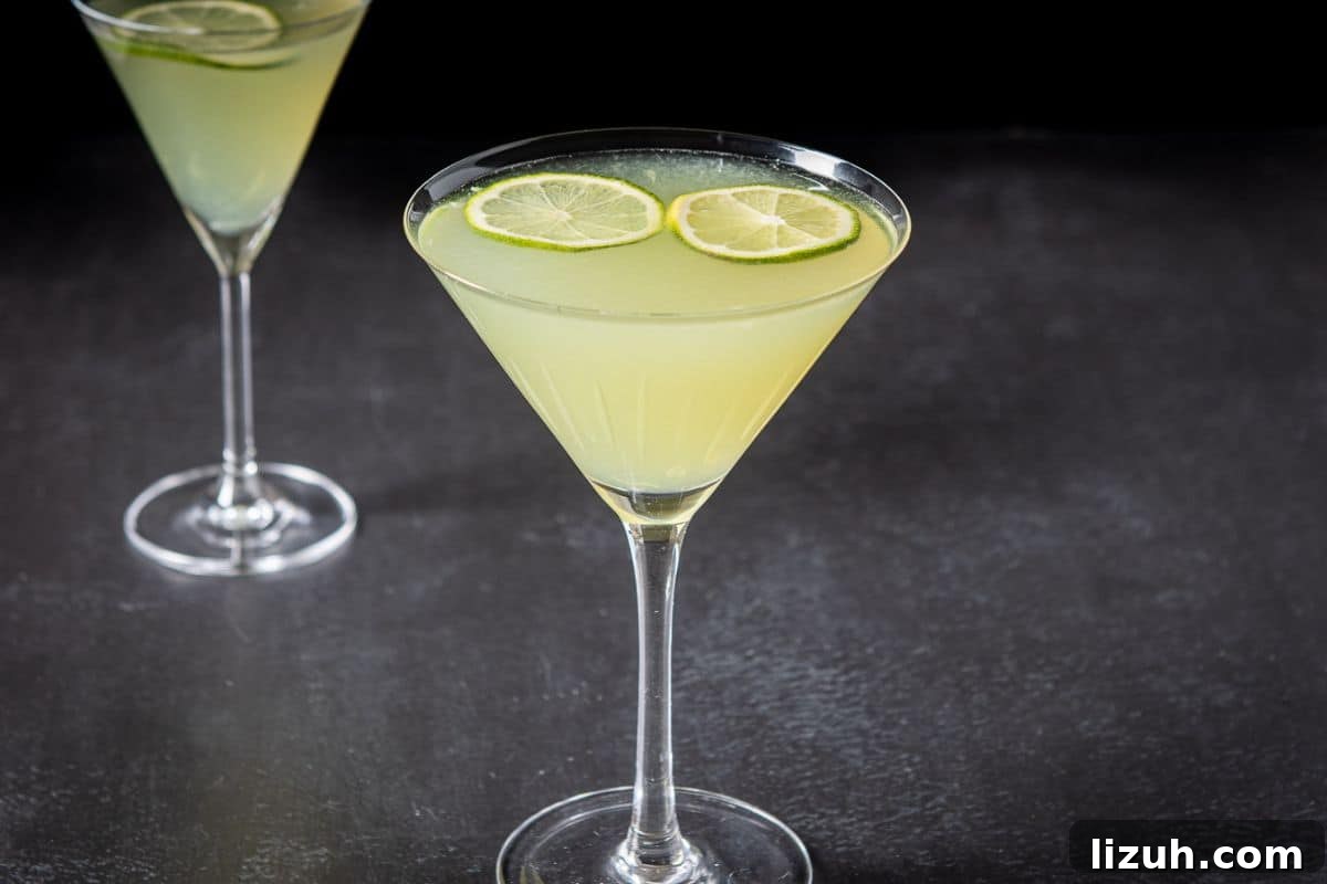 Classic Last Word Cocktail Recipe: How to Mix the Prohibition-Era Drink 3 Two cocktail glasses filled with the lime cocktail with two limes floating as garnish