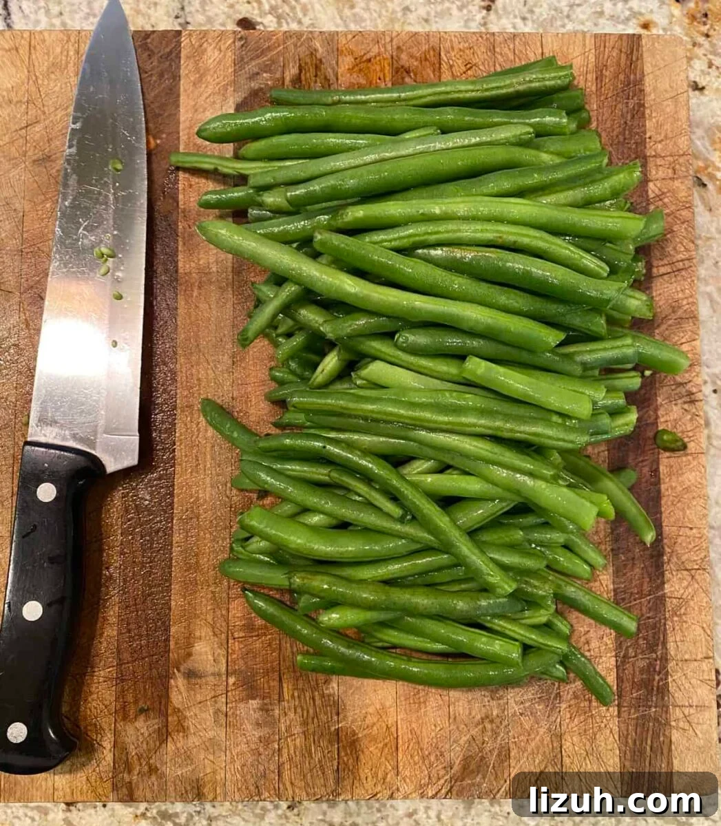 Green beans and a knife on a cutting board.