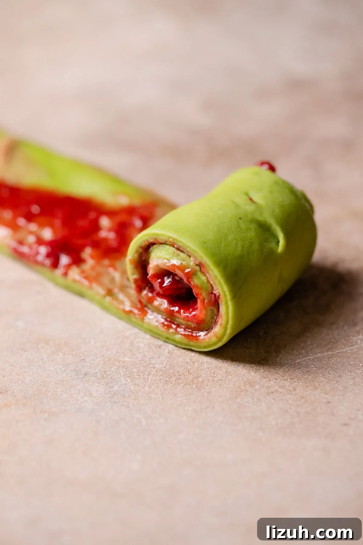 A strip of dough being rolled up into a cinnamon roll.