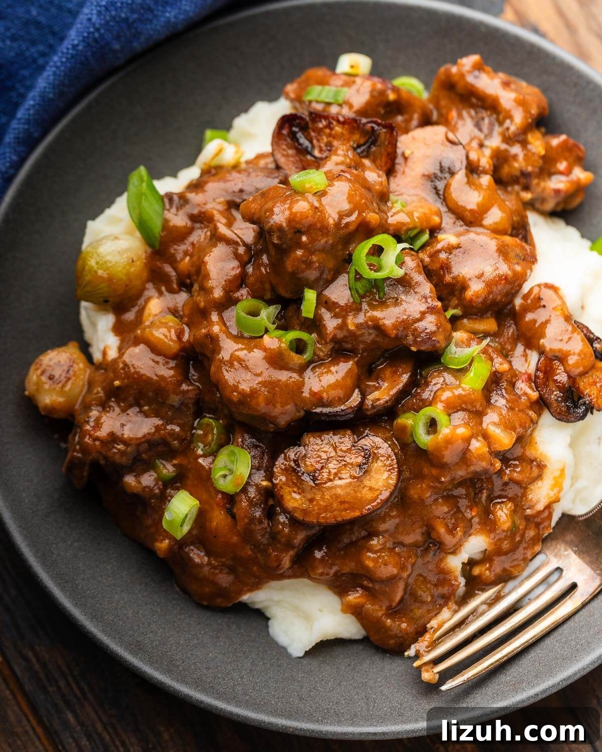 Sweet and Tangy Smothered Beef Tips Recipe 2 Grey plate with smothered beef tips topped with green onion.
