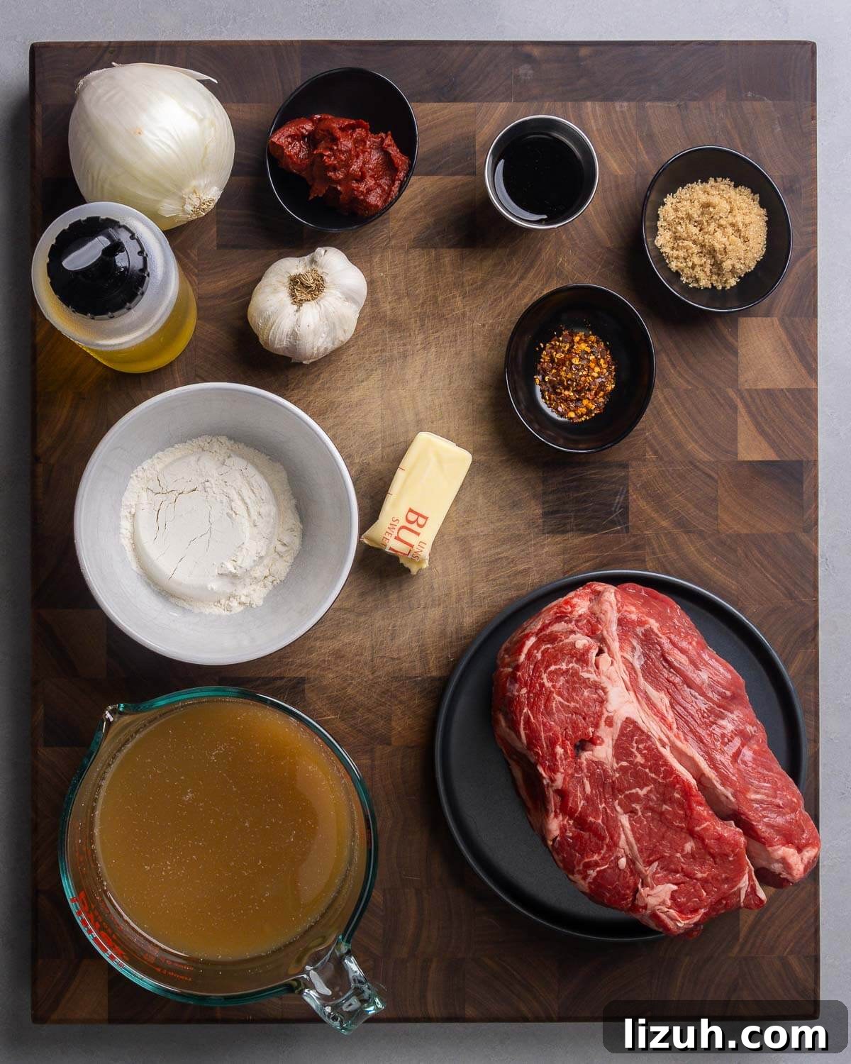 Sweet and Tangy Smothered Beef Tips Recipe 3 Ingredients shown: onion, olive oil, tomato paste, garlic, balsamic vinegar, worcestershire sauce, brown sugar, hot red pepper flakes, flour, butter, beef stock, and chuck roast.